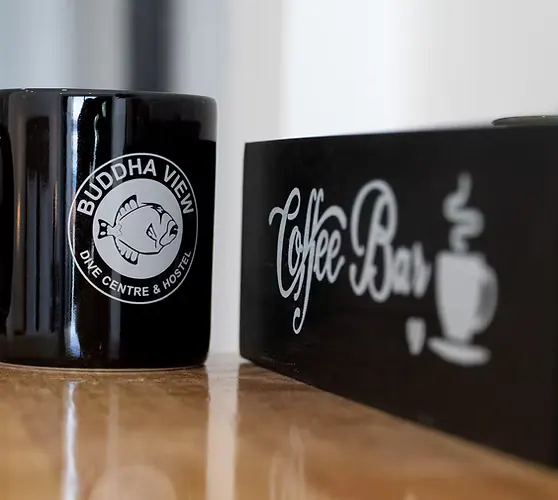 A Buddha View mug next to the Coffee Bar chalkboard at reception