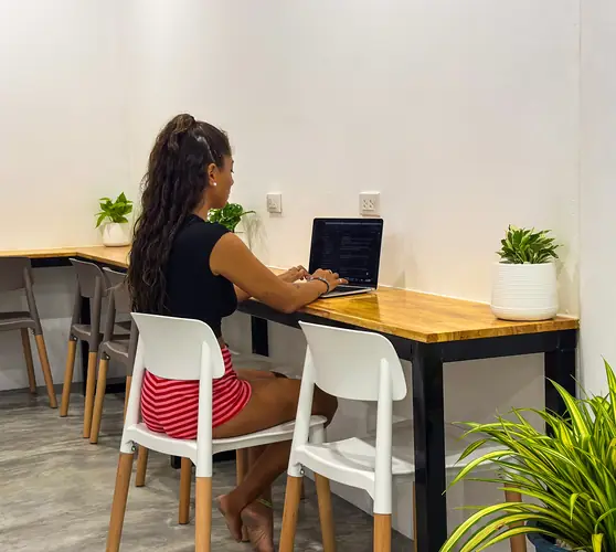 A guest working on her laptop at the long wooden coworking counter