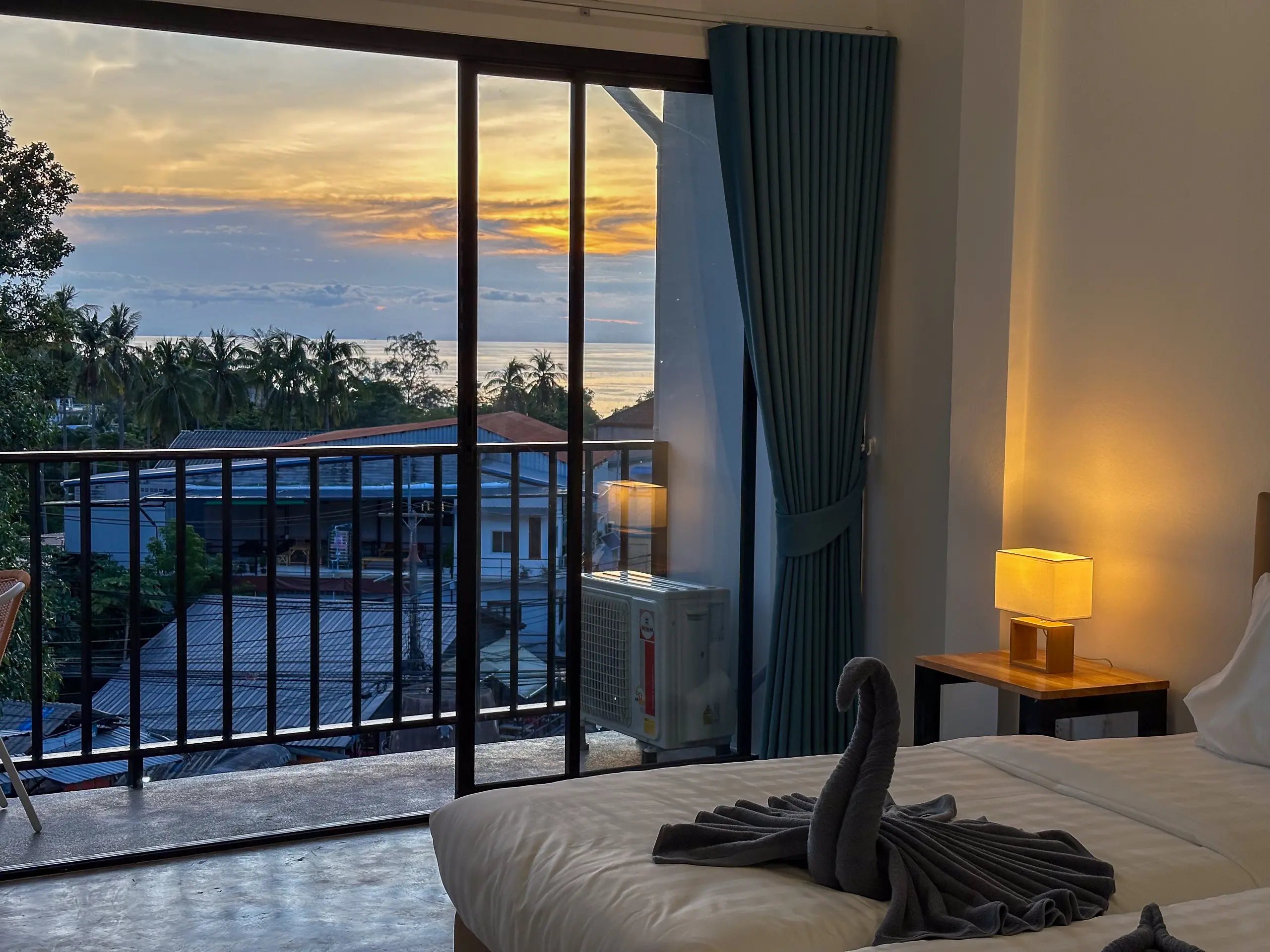 Twin beds at dusk with the balcony open onto the sunset